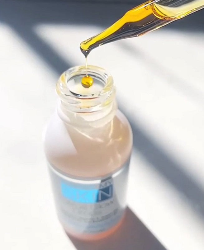 Citrus Glow Drops serum bottle with amber oil drop being poured