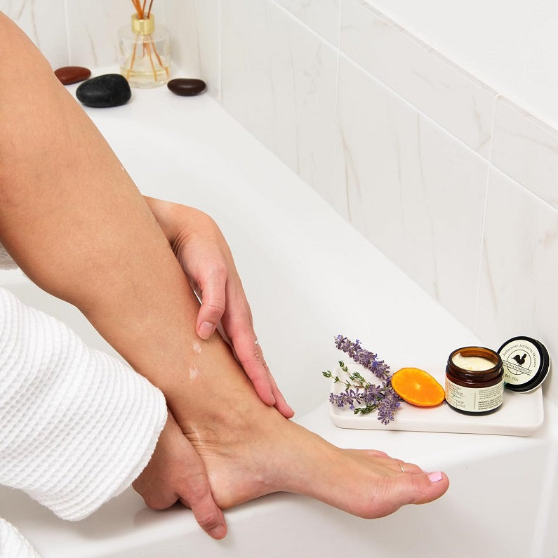 Whipped tallow balm in use: jar on tub shelf with balm on hands