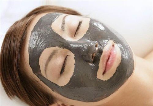 Woman with thick gray-black mud mask applied across face