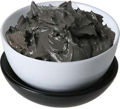 Dead Sea mud mask in a white bowl with thick black clay