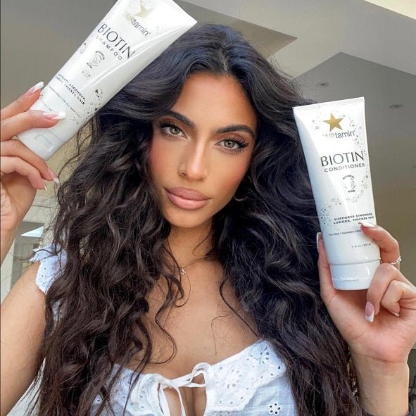 Biotin shampoo and conditioner tubes in hand, shown against long dark hair