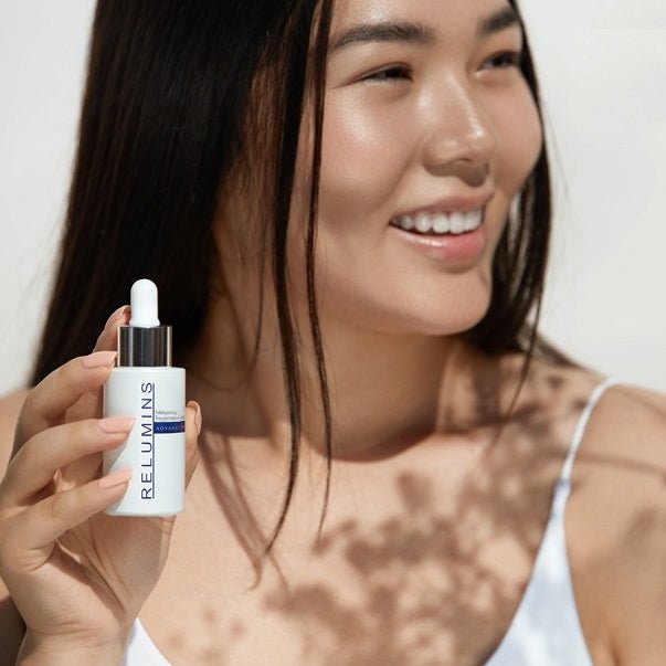 Woman holding Relumins serum bottle, white with silver cap