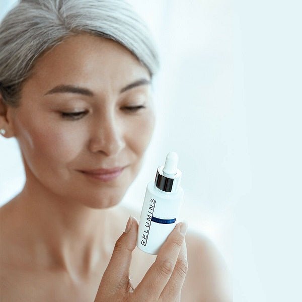 Woman holding an intensive brightening serum dropper bottle near cheek