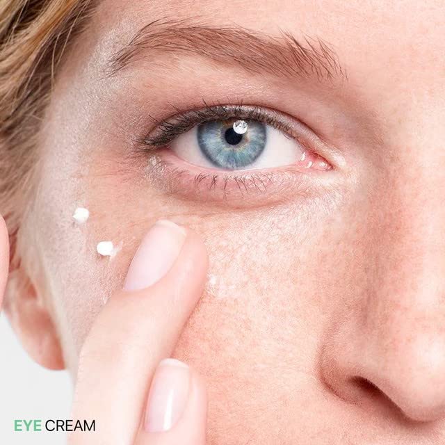 Close-up of under-eye area with white eye cream applied by fingertips